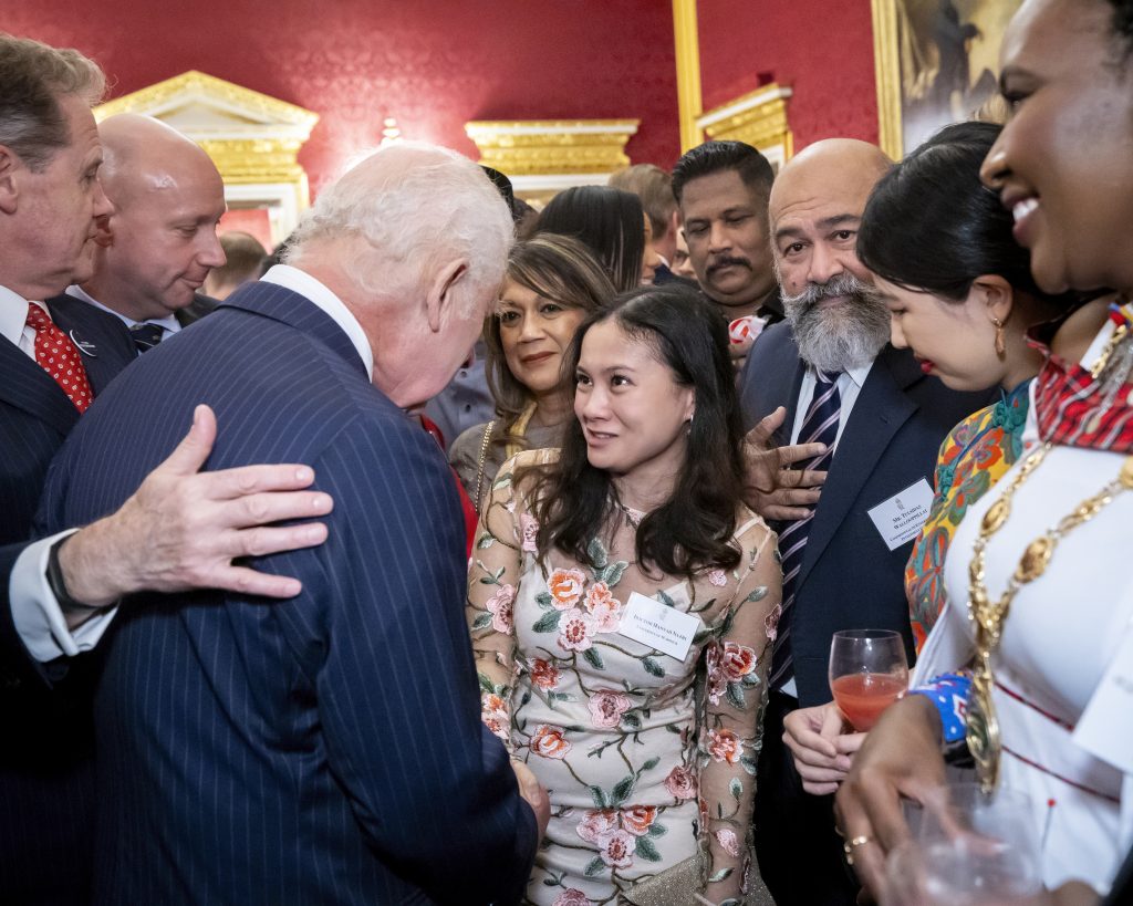 Dr Hannah Nazri (centre) with His Majesty King Charles III in formal attire gathered in a richly decorated room, engaged in conversation at a reception event.