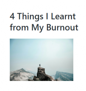Person standing on a rocky peak with snowy mountains in the background.